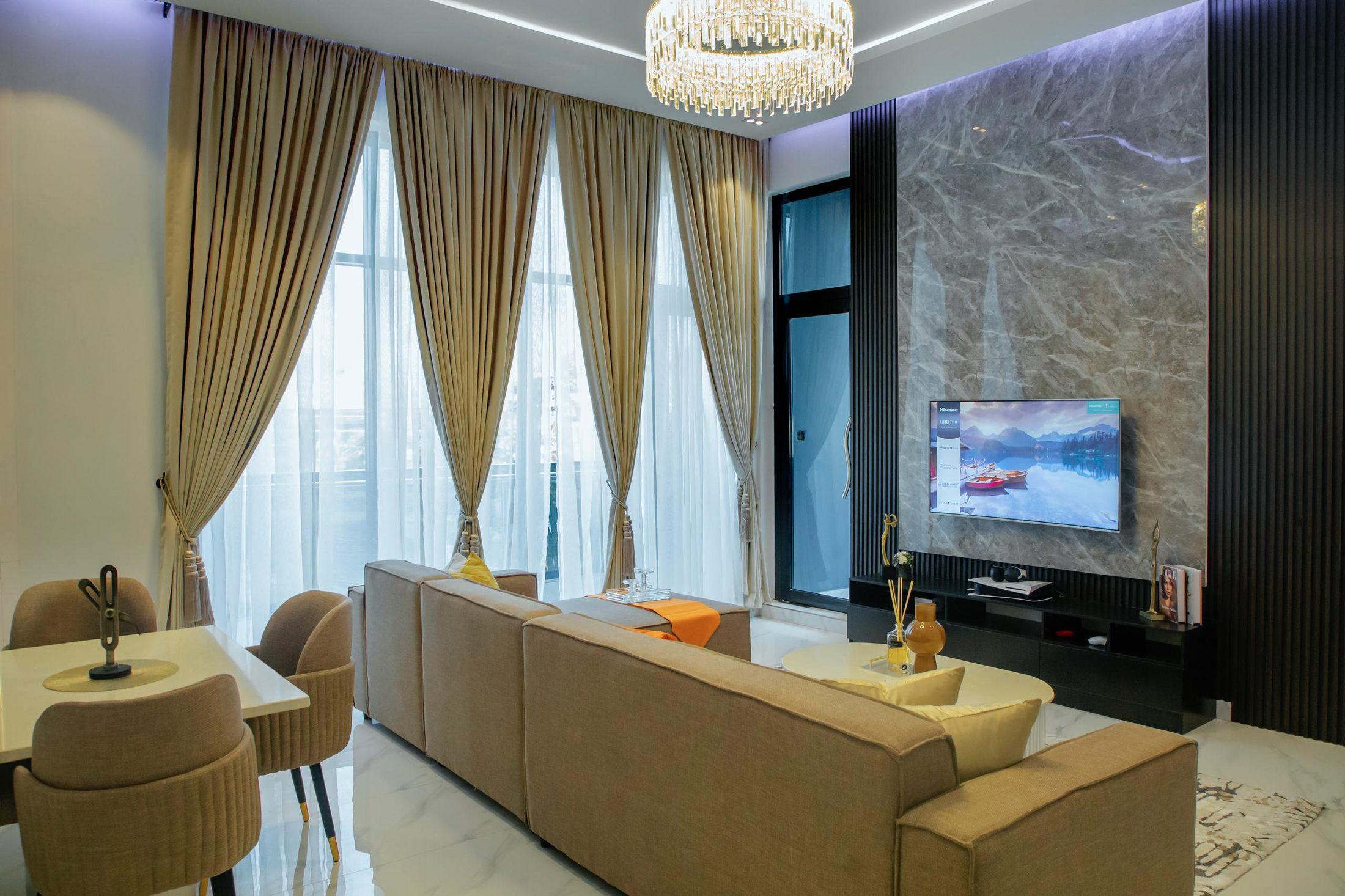 Lounge and dining area with a grey marble feature wall, black slatted panels and a crystal chandelier